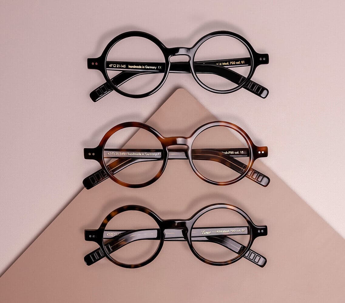 drei lunor korrektionsbrillen werden auf einem warmen hintergrund untereinander dargestellt